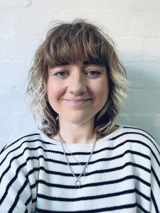 Lucy Kirk smiling and wearing a striped shirt